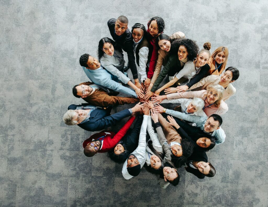 Top view of a diverse team of people joining hands in a collaborative and inclusive business environment, symbolizing unity and teamwork.